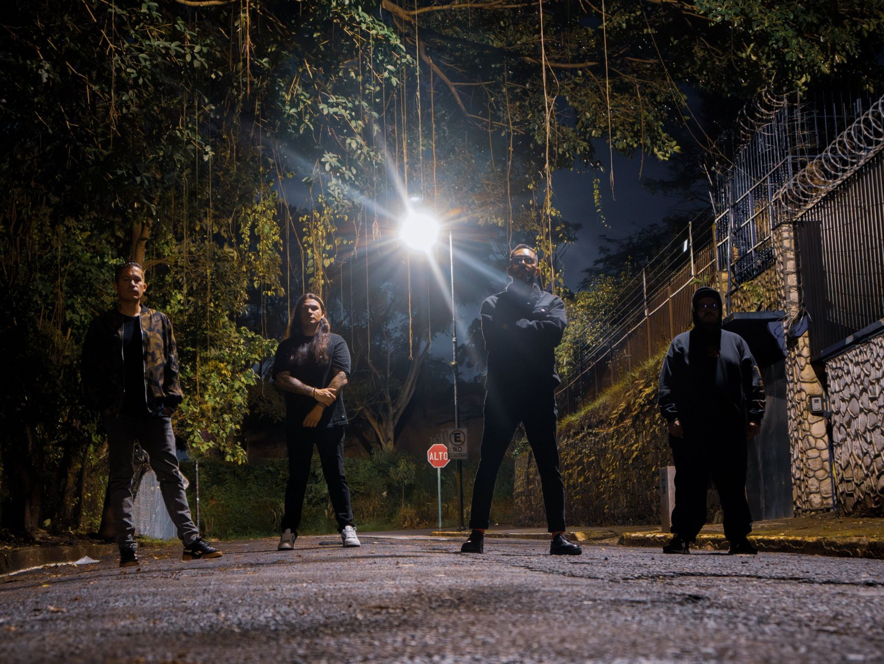 Los cuatro integrantes de noche en una calle bajo un farol