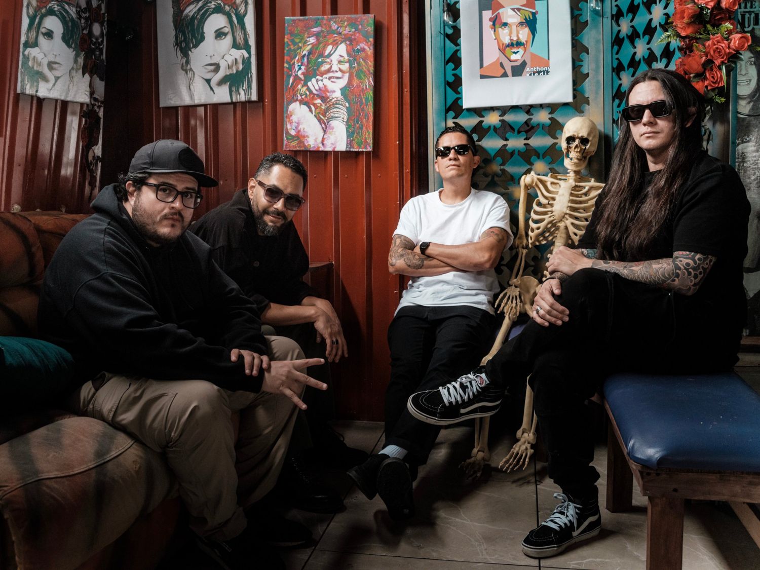La banda en un bar con un esqueleto y retratos en la pared